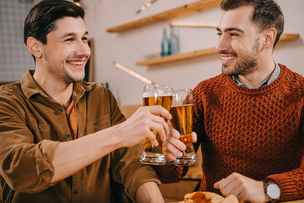 handsome men smiling while toasting glasses of beer  - Foto, Imagem
