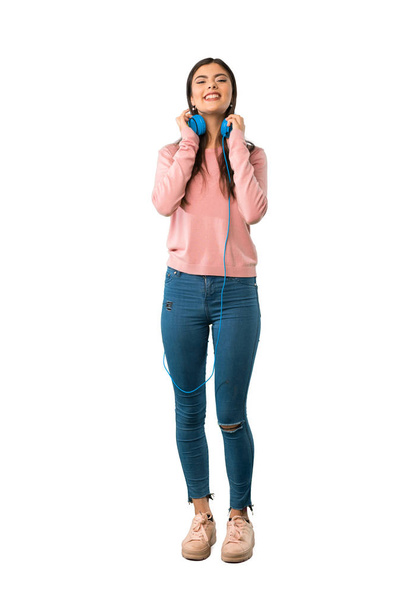 Een full-length schot van een tiener meisje met roze shirt met koptelefoon - Foto, afbeelding