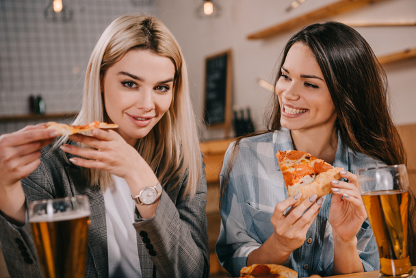 cheerful friends holding pieces of tasty pizza in bar - Valokuva, kuva