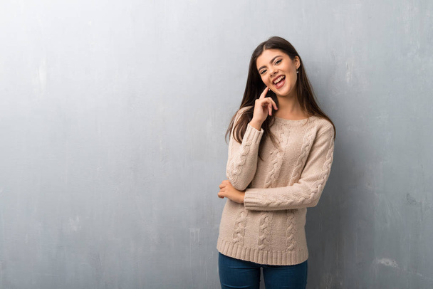 Κορίτσι έφηβος με πουλόβερ σε vintage τοίχο χαμογελά με γλυκιά έκφραση - Φωτογραφία, εικόνα