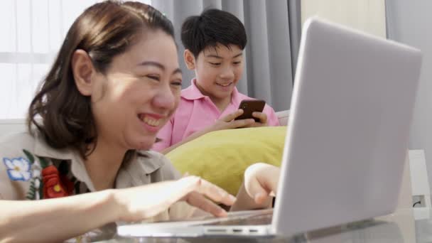 4 k aile yaşam tarzı bilgisayar oyunları oynuyor. Asya Anne ve oğlu dizüstü bilgisayar ile izlerken yüzünü gülümseme. - Video, Çekim