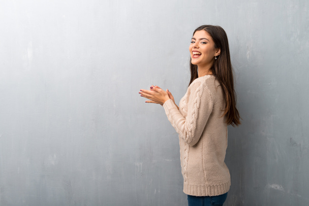 Teenager girl with sweater on a vintage wall applauding after presentation in a conference - Photo, image