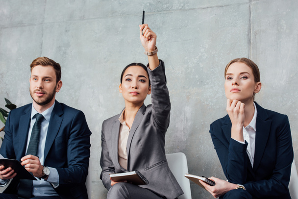 femme d'affaires concentrée lever la main tout en ayant une réunion avec des collègues au bureau
 - Photo, image