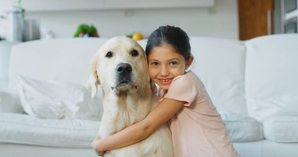 Portrait pf little girl playing and cuddling her dog in living room. Concept of love for animals, childhood, pedigree dog - Foto, imagen