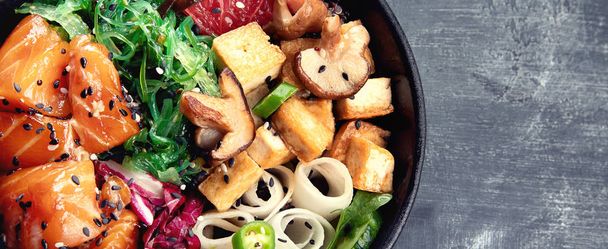 Poke bowl with salmon, quinoa, vegetables, fruits and tofu on dark background with copy space - Foto, Imagem