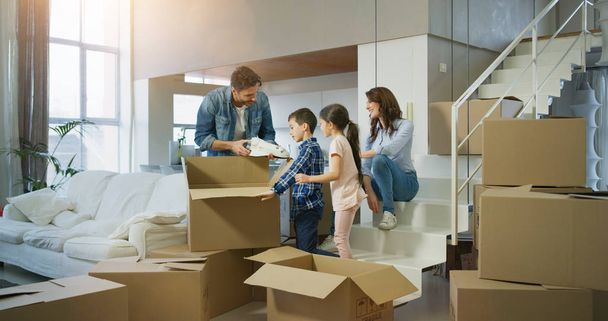 Portrait of happy family bought new house  and unpacking boxes for moving into. Concept of mortgage, insurance, property, real estate. - Foto, imagen