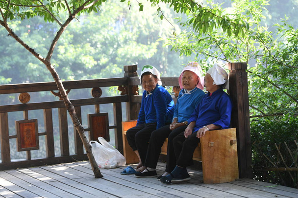 Elderly Chinese women of Miao ethnic minority rest in a Miao village in Leishan county, Qiandongnan Miao and Dong Autonomous Prefecture, southwest China's Guizhou province, 13 May 2017 - Valokuva, kuva