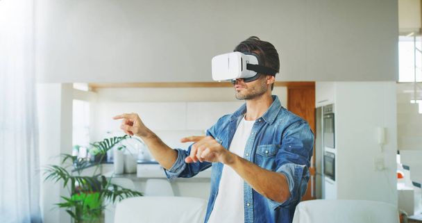 Portrait of handsome man using vr glasses in living room. Concept of innovation technology, lifestyle, entertainment. - Photo, image