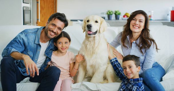 Portrait of happy family with a dog having fun together in living room. Concept of happy family, love for animals, childhood - 写真・画像