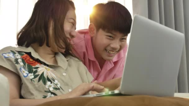 4K estilo de vida familiar está jugando juegos de ordenador. asiático madre y hijo viendo en portátil ordenador con sonrisa cara
. - Metraje, vídeo