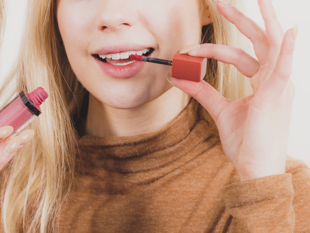 Happy cheerful woman is about to use red tinted lips gloss on her lip. Make up concept. - Foto, Imagen