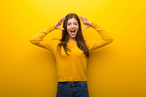 Teenager girl on vibrant yellow background with surprise and shocked facial expression - Photo, Image