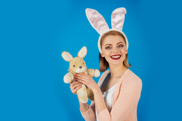 Woman in rabbit bunny ears. Egg hunt. Easter eggs as traditional food. Spring holiday. Girl with hare toy. happy woman in bunny ears with toy. Happy easter. copy space. Look what i got - Foto, Imagen