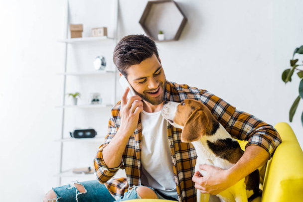 handsome smiling man talking on smartphone and looking at dog - Foto, immagini