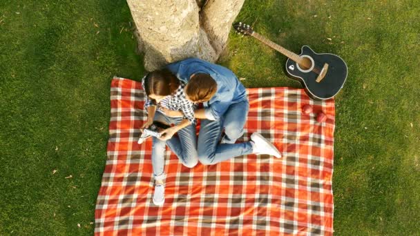 Onnellinen pari ottaa kuvan itsestään älypuhelimella vihreällä nurmikolla
. - Materiaali, video