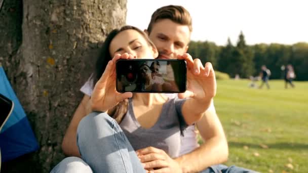 Boldog pár vesz egy képet magukat egy smartphone, a zöld gyep. - Felvétel, videó