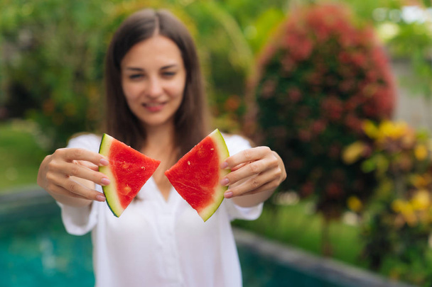 Close up of womans hands make butterfly shape from two pieces of watermelon with blurred girl on background - Fotoğraf, Görsel