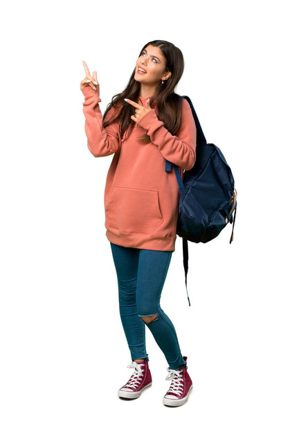 A full-length shot of a Teenager girl with sweatshirt and backpack pointing with the index finger and looking up - Foto, Imagen
