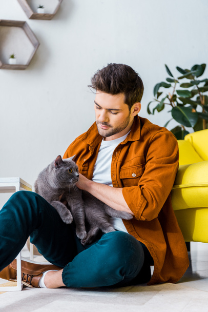 casual smiling man sitting on floor with cute cat - Fotografie, Obrázek
