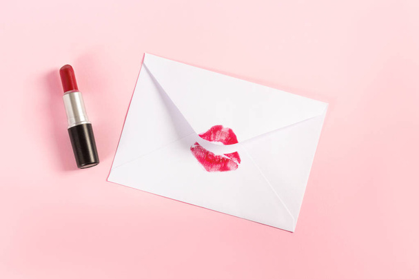 Красная помада поцелуй на белом конверте на розовом пастельном фоне. - Фото, изображение