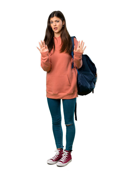 A full-length shot of a Teenager girl with sweatshirt and backpack making stop gesture with both hands - Photo, Image