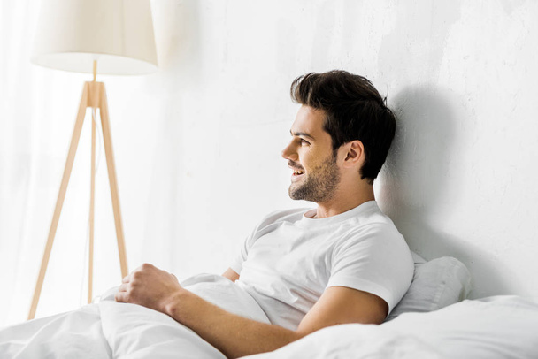 jeune homme riant couché dans son lit le matin
 - Photo, image
