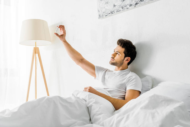 handsome man taking selfie on smartphone in bedroom - Foto, Bild