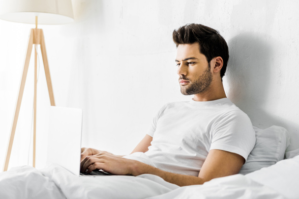 poważny człowiek za pomocą laptopa w łóżku rano - Zdjęcie, obraz
