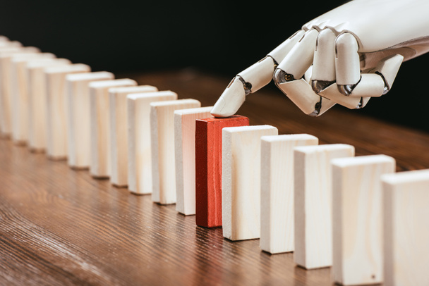 selectieve aandacht van robotic hand plukken rode houten baksteen uit rij van blokken op Bureau - Foto, afbeelding