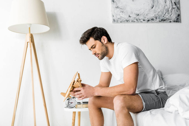 young man looking at wooden toy plane in bedroom - Photo, Image