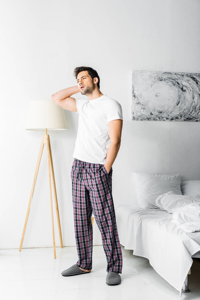 tired man in pajamas looking away in bedroom in the morning - Photo, Image