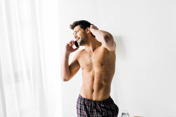 homem sem camisa falando no smartphone no quarto
 - Foto, Imagem