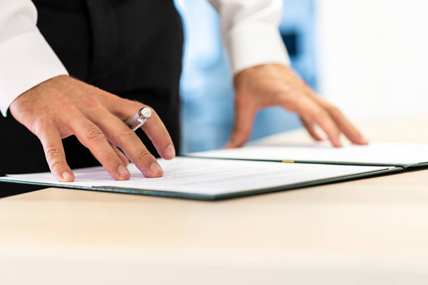 Business executive reviewing important document or contract in a folder before signing it. - Photo, Image