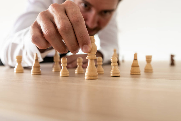 Business leader arranging chess pieces with king in the leading position in a conceptual image of business strategy and human resources. - Zdjęcie, obraz