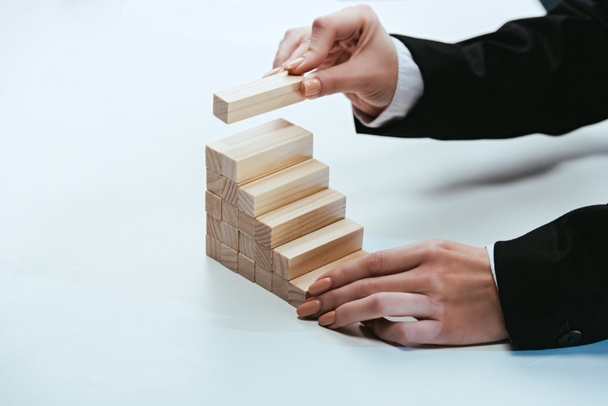 cropped view of woman putting wooden brick on top of wooden blocks symbolizing career ladder - Photo, Image