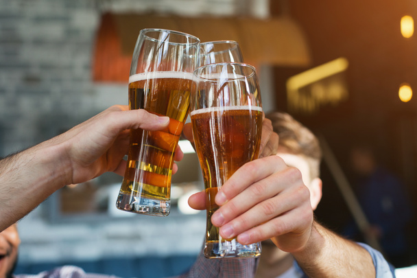 Miespuoliset ystävät juomassa olutta ja clking lasit
 - Valokuva, kuva