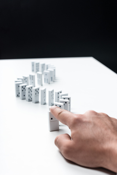 Kırpılan izole siyah üzerine beyaz masaya domino satır gösteren adam görünümünü - Fotoğraf, Görsel