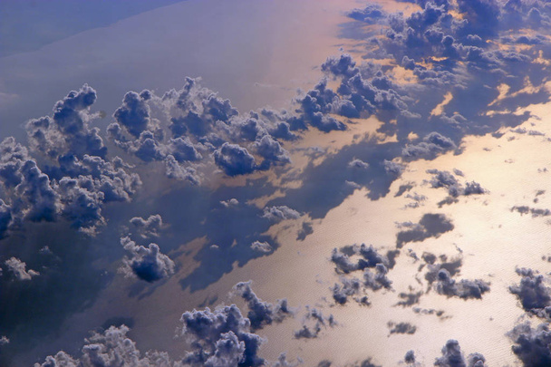 Beautiful heaven panorama from above. Dark clouds moving above water surface of sea. Landscape with sun reflected in sea surface. Shadow of clouds on water surface of sea. View from plane - Photo, Image