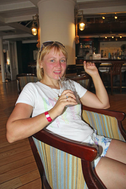 Młoda kobieta picia gin tonic przez słomkę. Ładna dziewczyna, ciesząc się wakacje. Atrakcyjna kobieta uśmiechając się i picia alkogolic dring w barze podczas wakacji - Zdjęcie, obraz