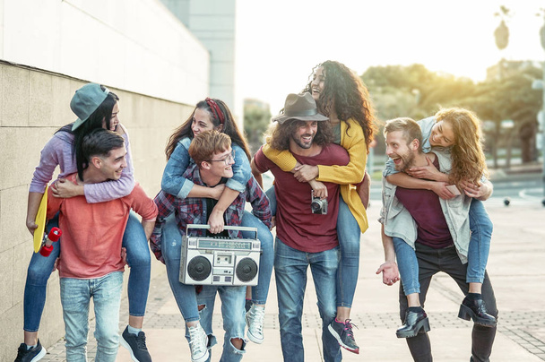 Happy millennials friends having fun outdoor - Young people piggybacking while laughing and walking together in the city center - Friendship, generation z, teenager and youth lifestyle concept - Photo, Image