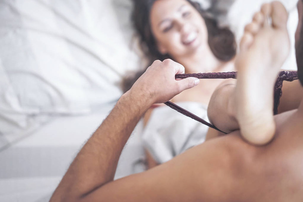 Boyfriend putting off his girlfriend's panties before having sex on bed - Passionate couple having sexy and intimate moments in the bedroom - People relationship, romance love and sexual concept - Photo, Image