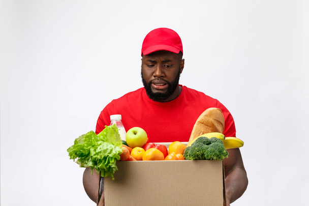 Portret Afrykańczyka w czerwonej koszuli. podnoszenie ciężkich pudełek na zakupy przeciwko izolacji na białym tle. - Zdjęcie, obraz