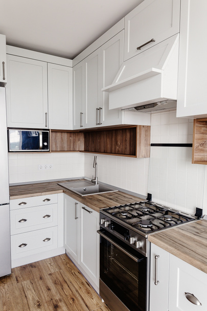 スタイリッシュなキッチン インテリア デザイン。グレー色と鋼のオーブン、冷蔵庫、シンク、木製卓上型の高級モダンなキッチン家具。北欧風のグレーのキャビネット。家の改修 - 写真・画像