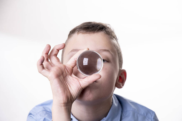 Boy looks dreamily into a glass ball to predict the future - Photo, Image