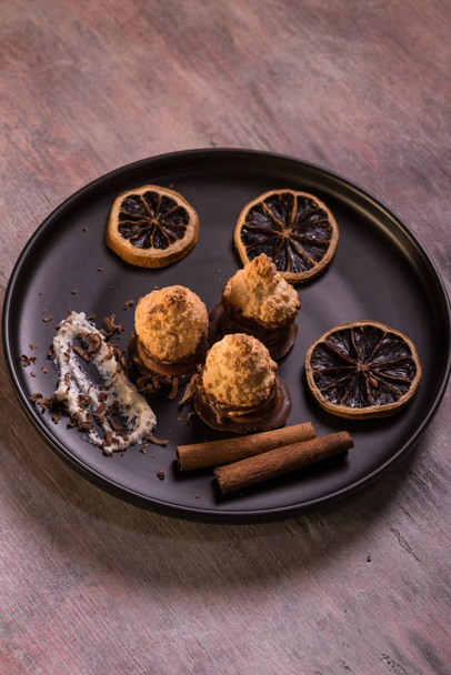 Few pieces of baked sweets on dark plate with orange rings - Fotografie, Obrázek