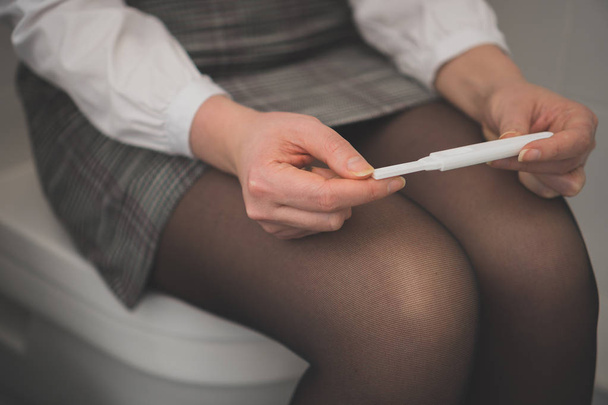 Жінка з тестом на вагітність сидить у туалеті
. - Фото, зображення