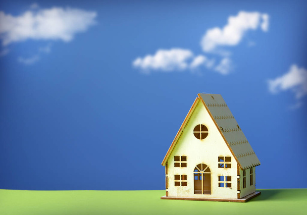 klein model van huis met blauwe lucht en de wolken in de achtergrond - closeup - Foto, afbeelding