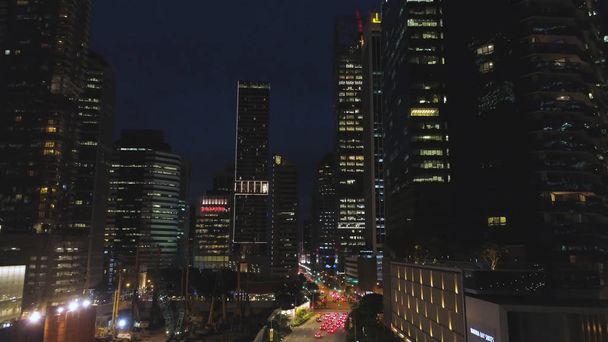 Top view of street with cars and modern buildings in big Chinese city at night. Shot. Night aerial view of city center with its road, moving cars, lights of skyscrapers, night life concept. - Photo, Image