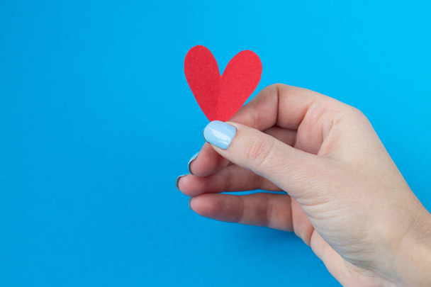 hand holding a red heart on a blue background. Background for Valentine's day - Fotografie, Obrázek