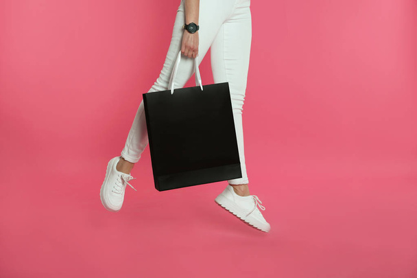 Woman jumping with paper shopping bag on color background. Mock up for design - Foto, Bild